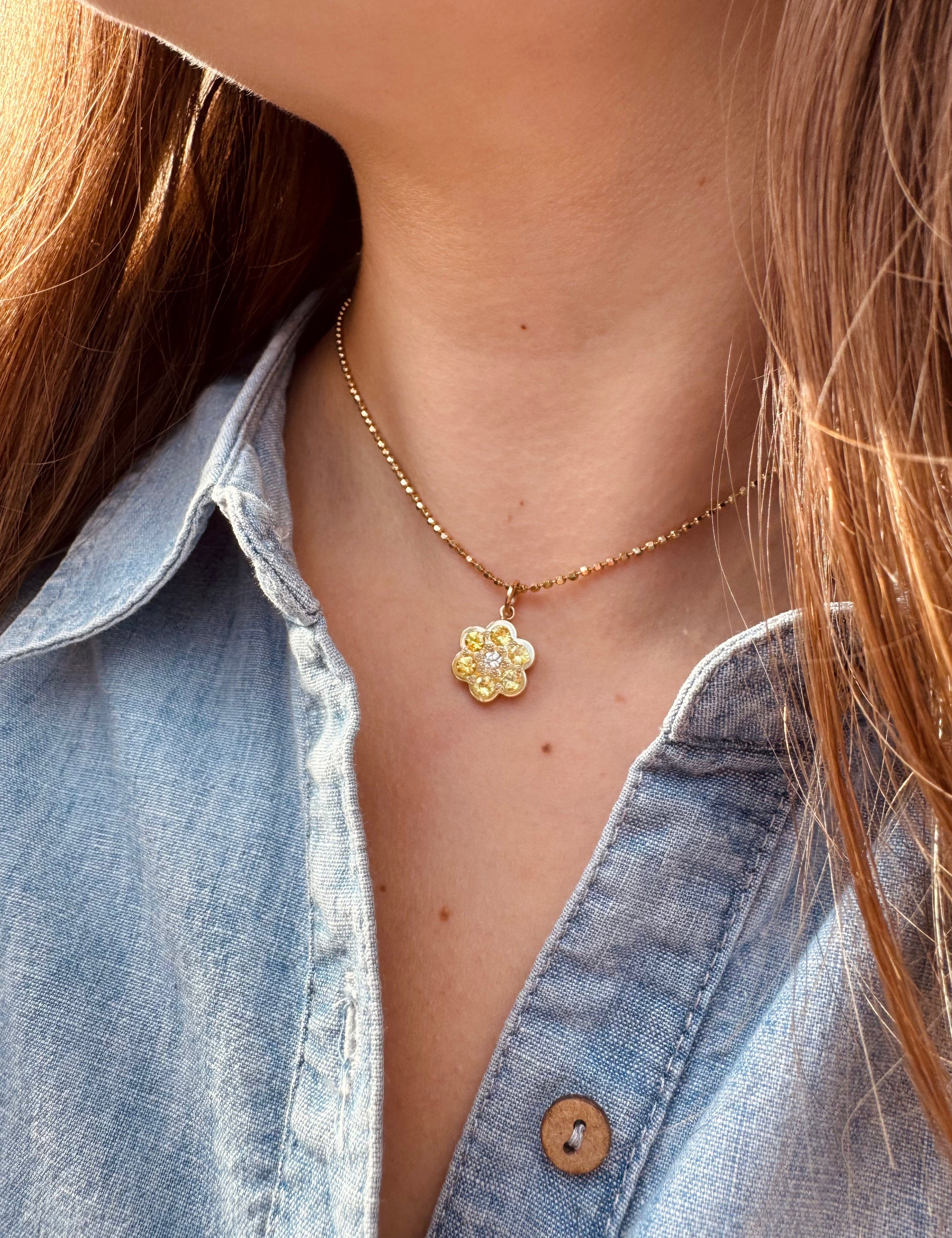 Person wearing Julez Bryant fine jewelry 14k yellow gold Genu Flower Pendant with Sapphires