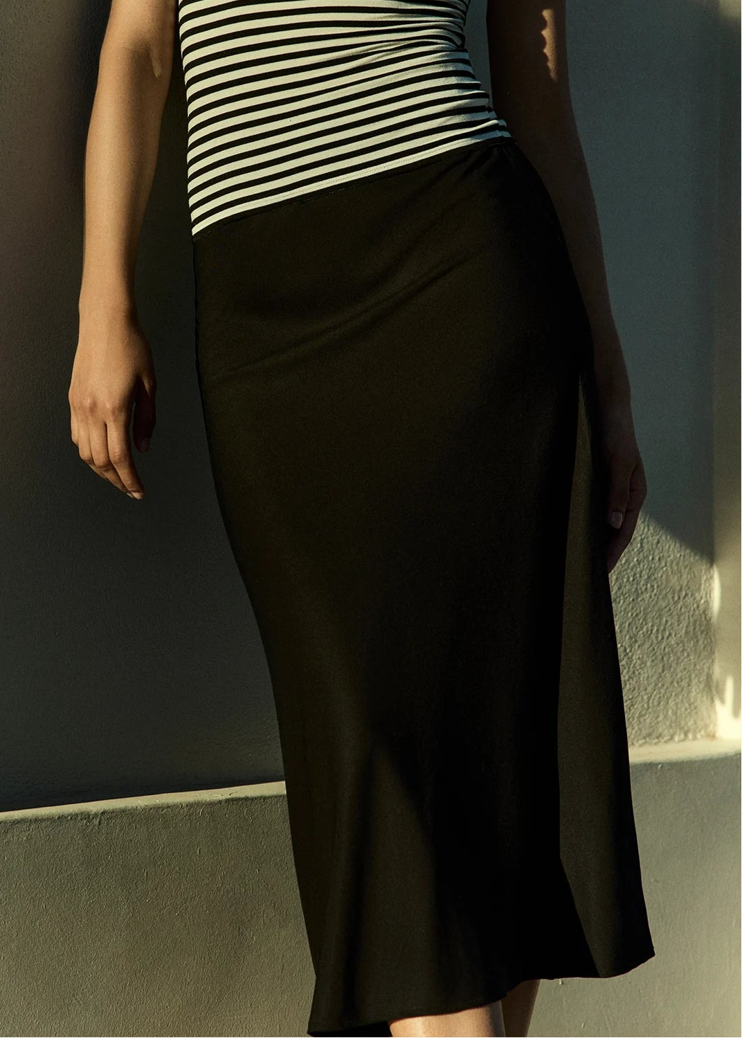 person wearing anemos womens Rey Bias-Cut Midi Skirt in Black stretch viscose